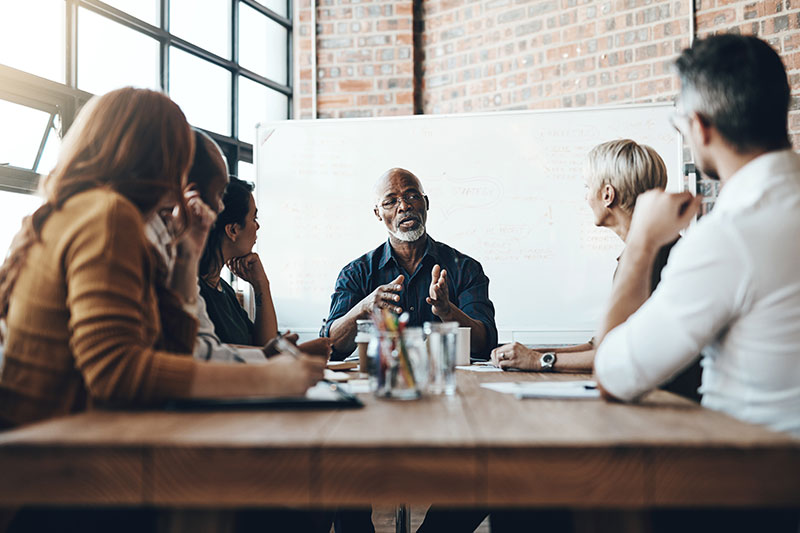 Colleagues looking at cheerful businesswoman in meeting at creative office